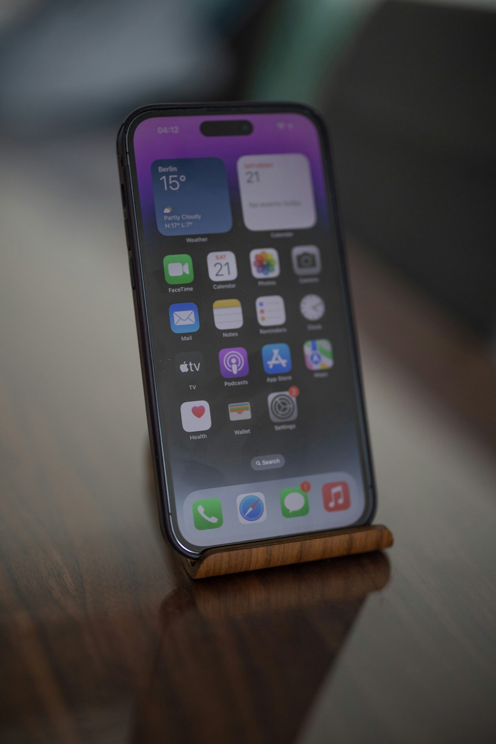 a cell phone sitting on top of a wooden table and another cell phone is placed on surface 
